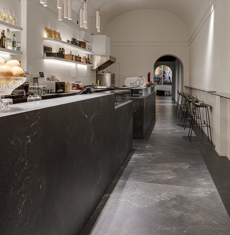 Piastrelle grande formato grigio scuro effetto pietra per pavimento e bancone caffè.