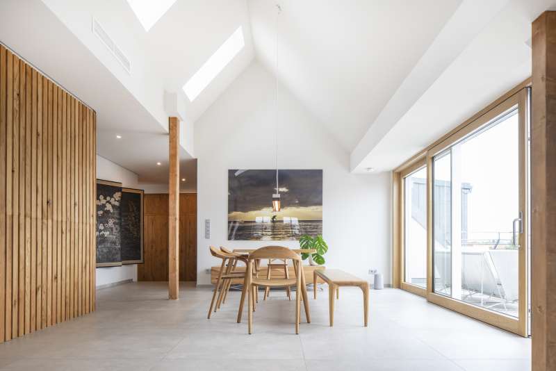 Ampia zona pranzo con piastrelle chiare, accenti in legno e molta luce naturale.