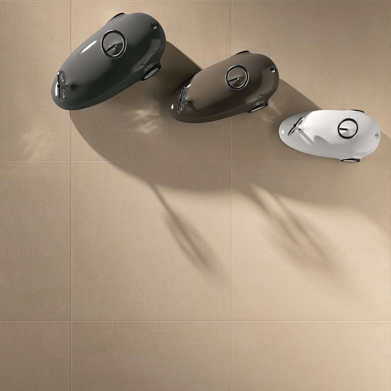 Piastrelle chiare di grande formato in beige sabbia con tre oggetti di design moderno.