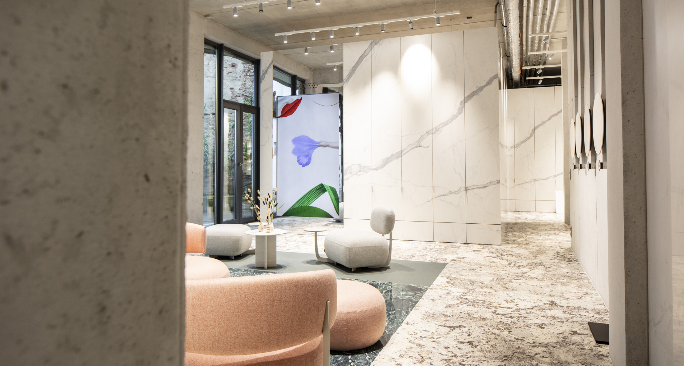 Ambiente moderno con piastrelle grande formato effetto marmo chiaro a parete e pavimento, con mobili lounge eleganti.